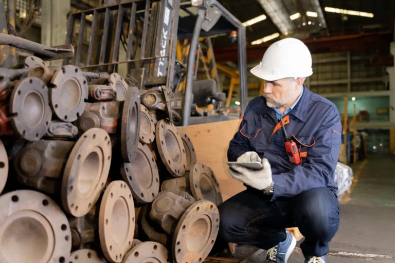 Worker inspecting industrial valves in a factory, representing quality control in the supply chain